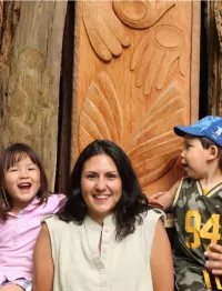 women with children in front of a totem
